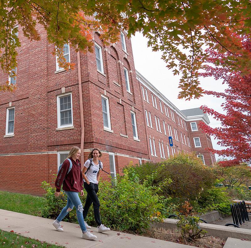 Two students walking together between Wood and Haven Halls.