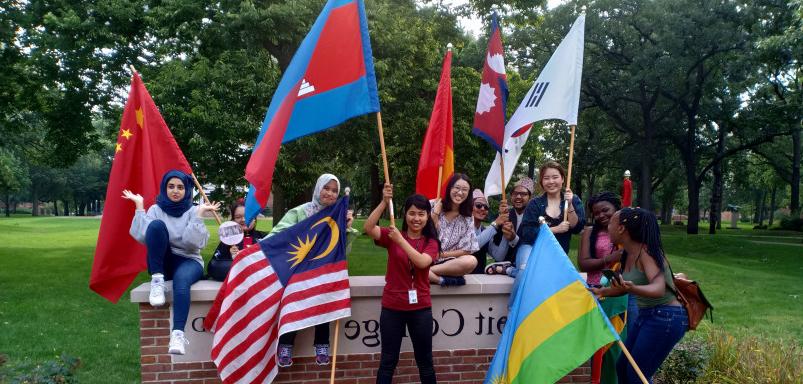 International students wave their flags in front of the Beloit College sign following Convocation...